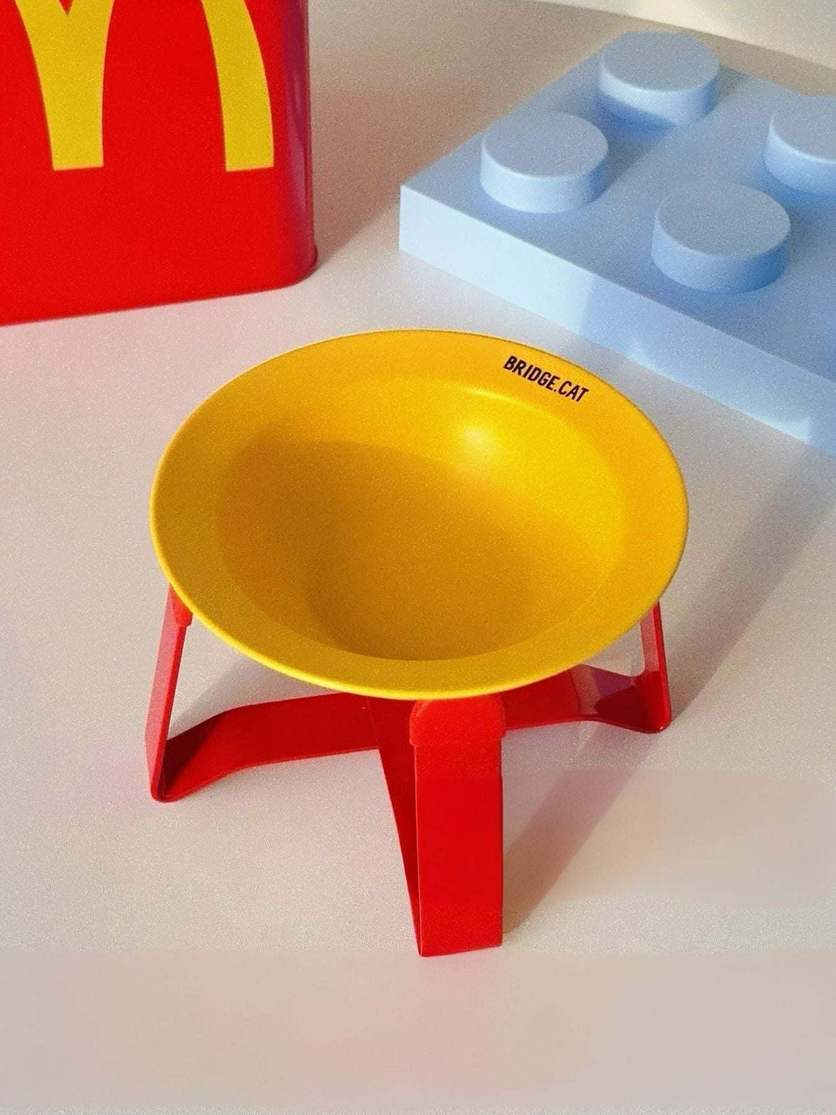 Red airtight pet food storage container with yellow logo and attached scoop